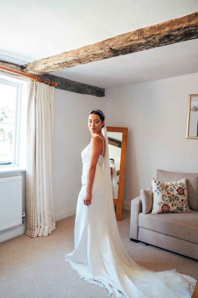 bride ready stands in bedroom at Blake Hall