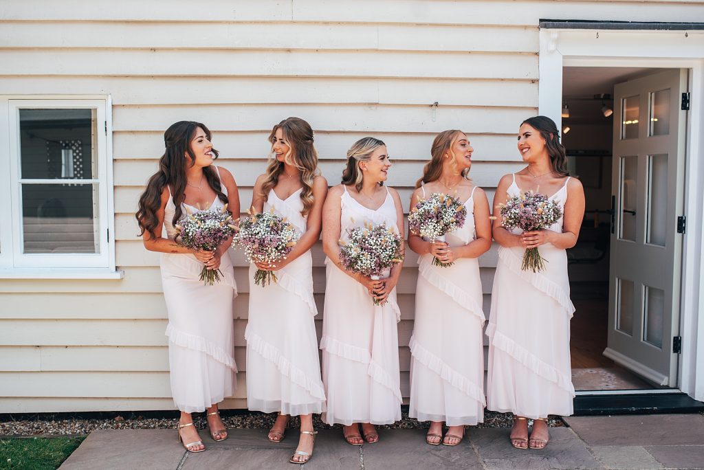 bridesmaids in pink laugh as they wait for ceremony