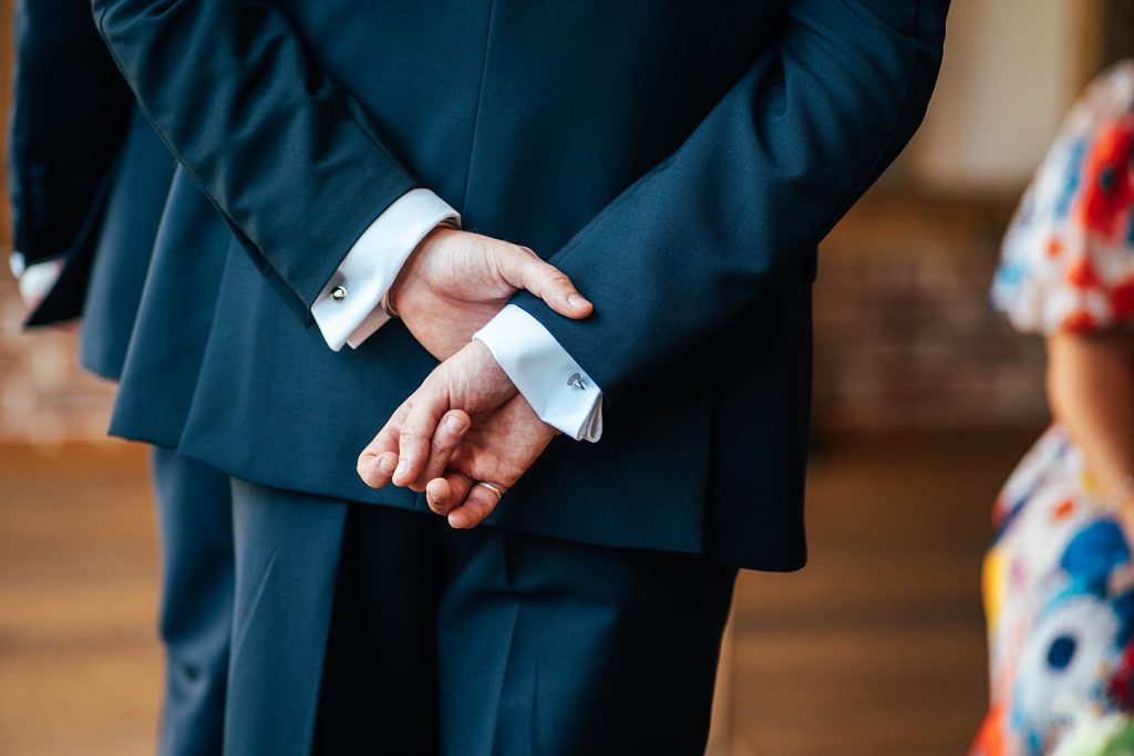 groom is nervous and holds his hands behind his back
