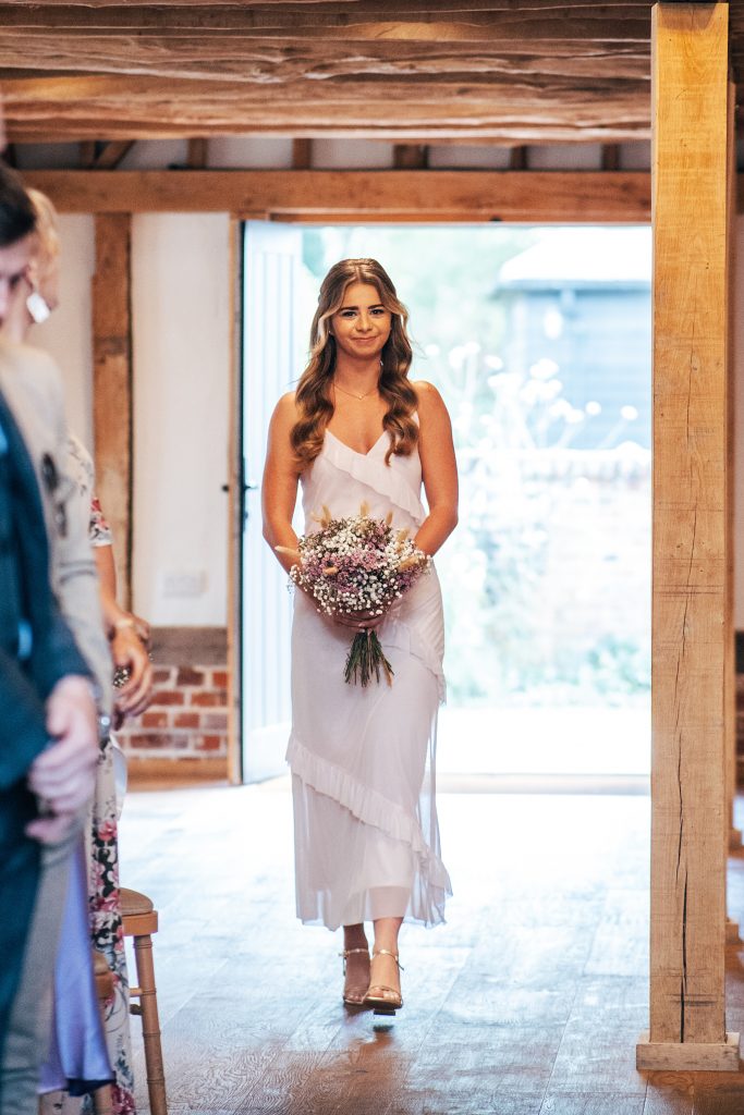 bridesmaid in pink walks down aisle