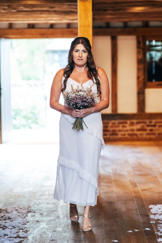 bridesmaid in pink walks down aisle