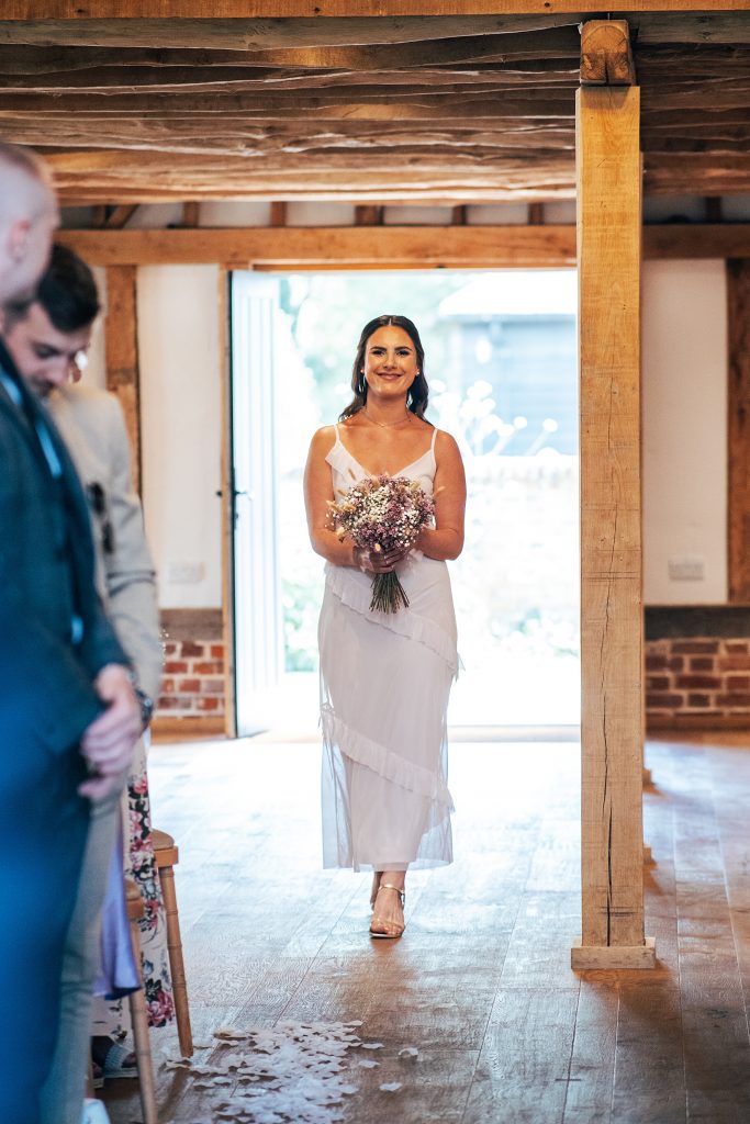 bridesmaid in pink walks down aisle