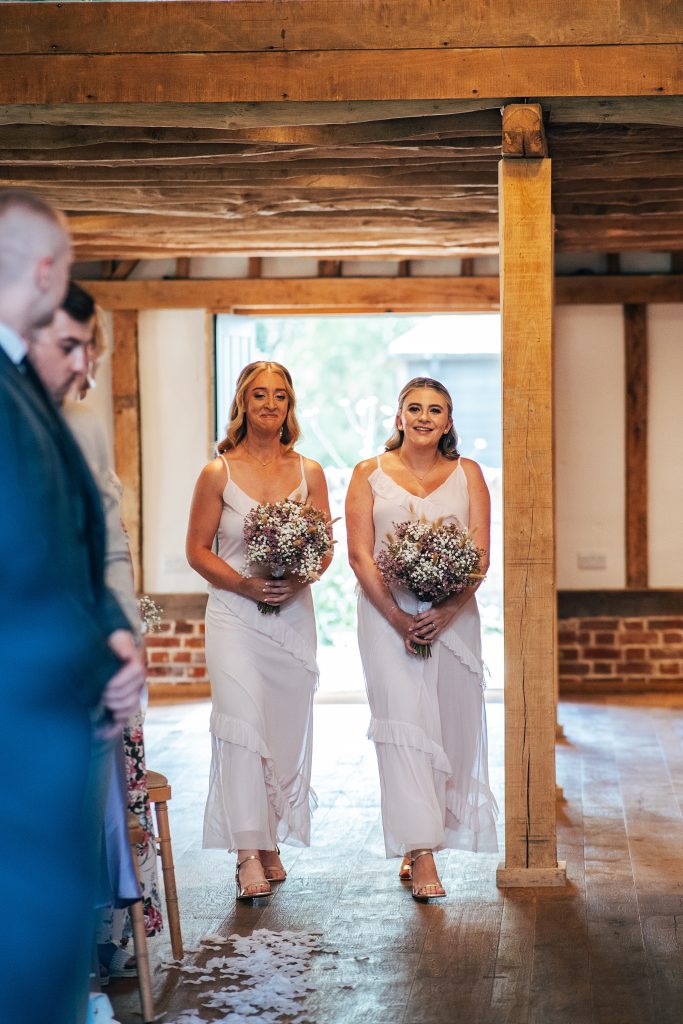 two bridesmaids in pink walk down aisle