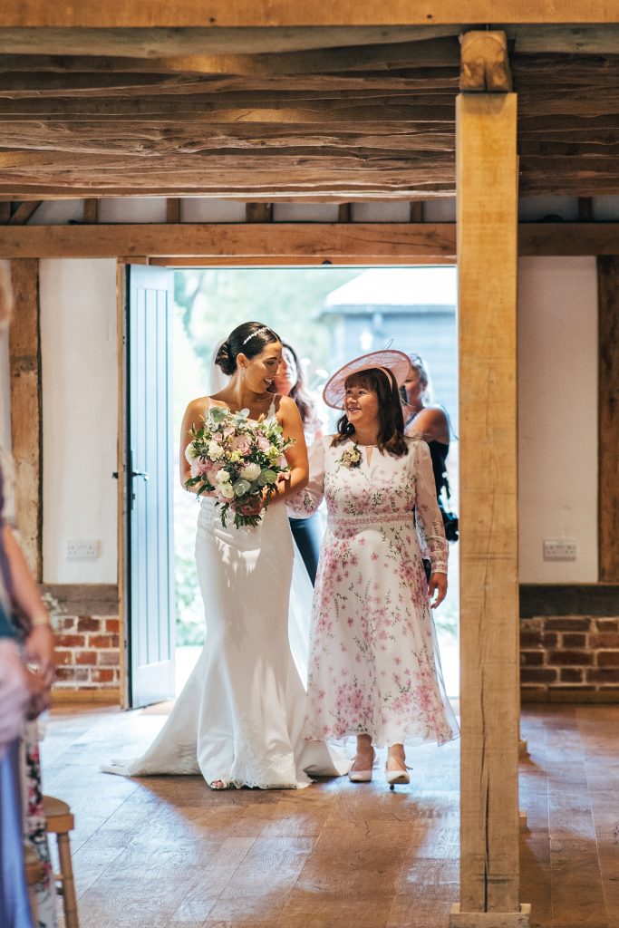 bride and mum look at each other as they walk down aisle
