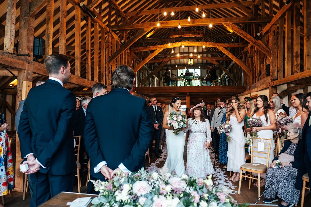 bride and mum walk down aisle towards groom