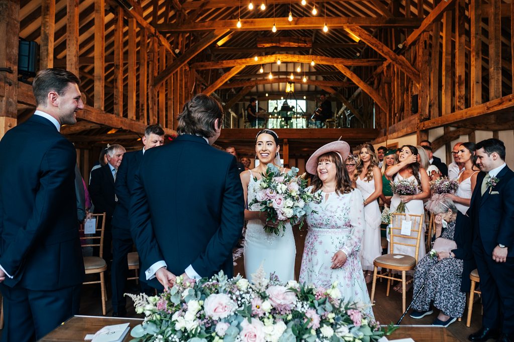 smiling bride and mum greet groom at top of aisle