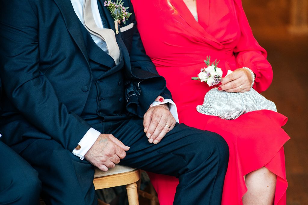 close up of grooms parents holding hands during ceremony