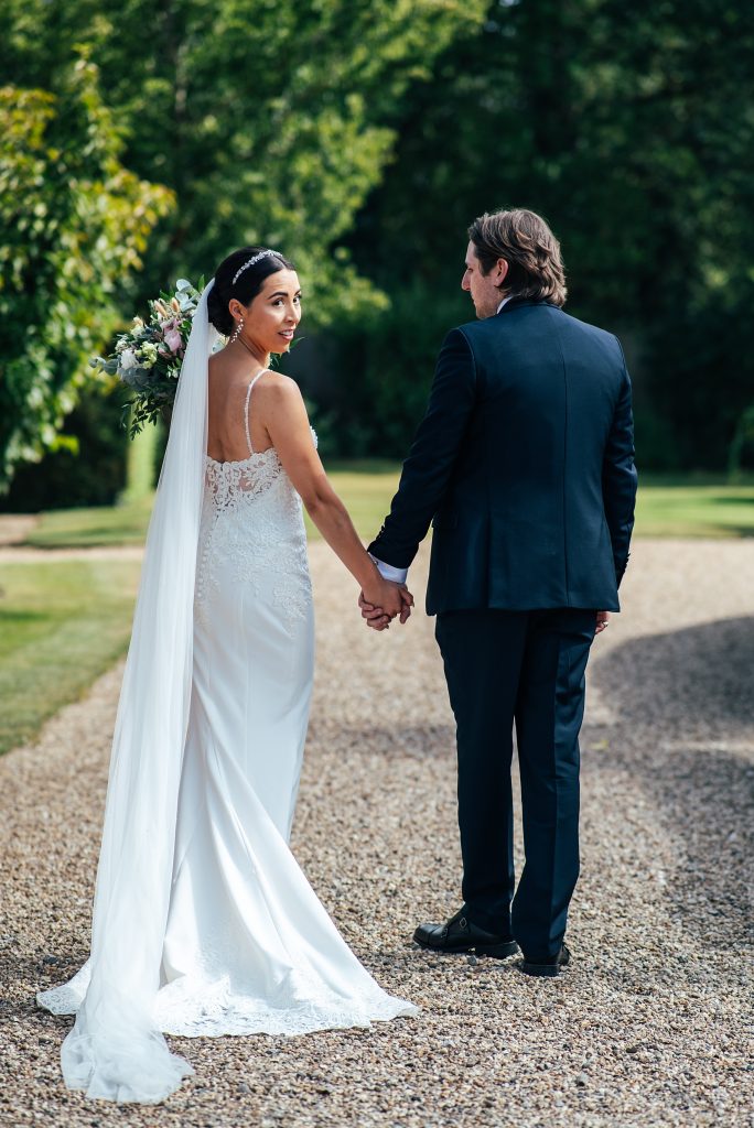 bride looks behind as she walks with groom to gardens