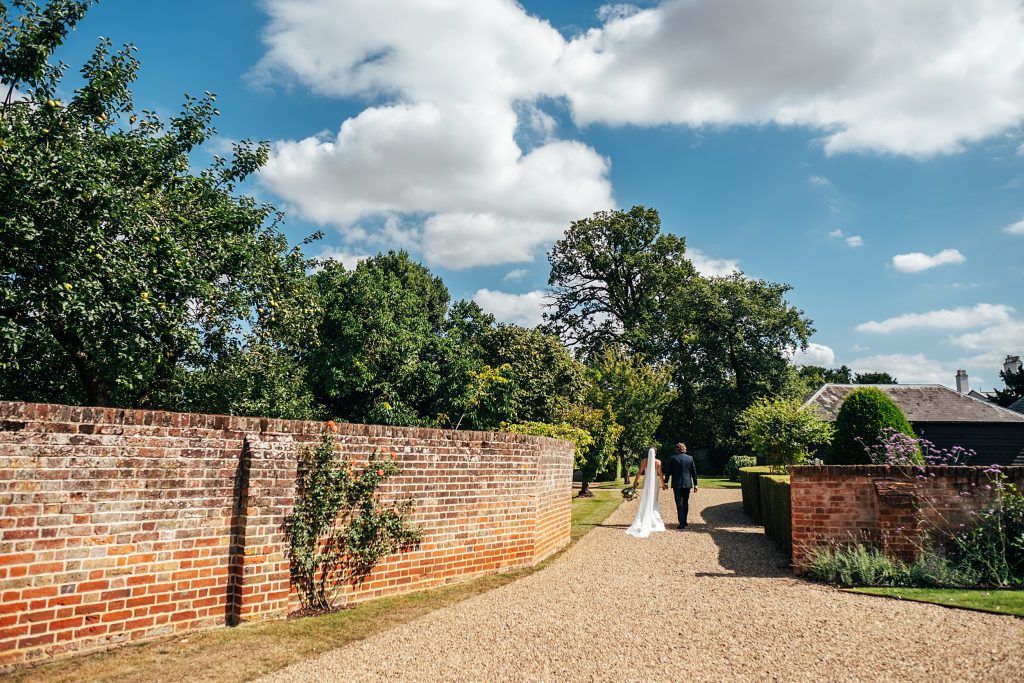wide shot of bride and groom as they walk to gardens