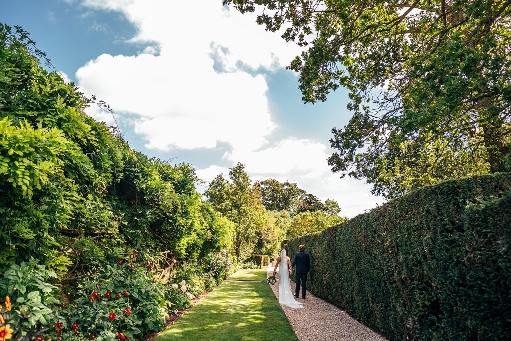 bride and groom walk in walled gardens