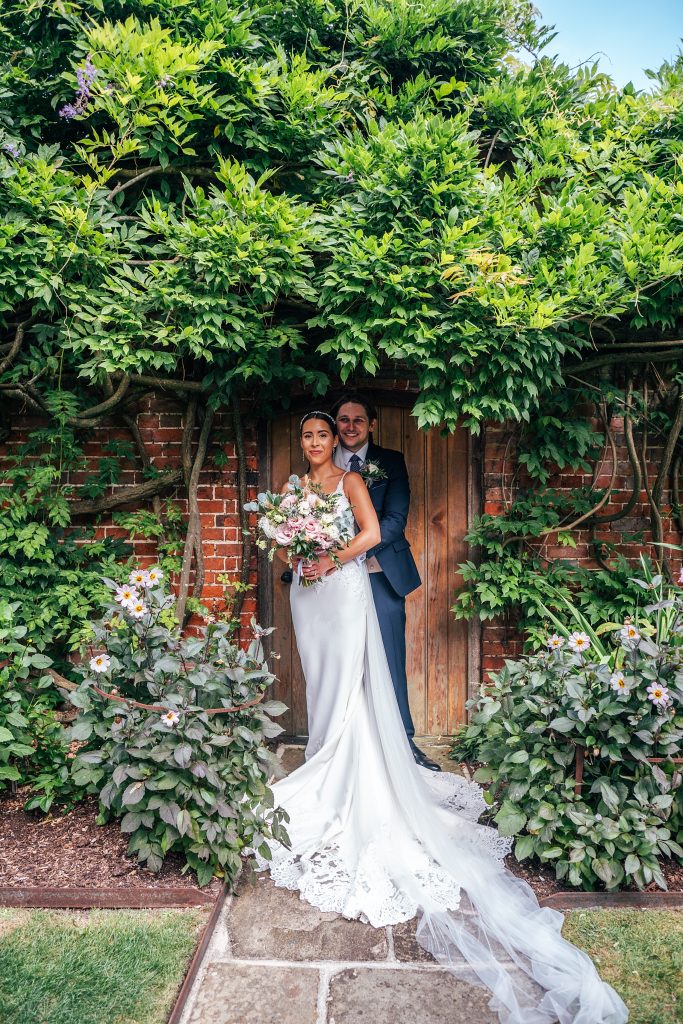 bride and groom stand in doorway in walled gardens