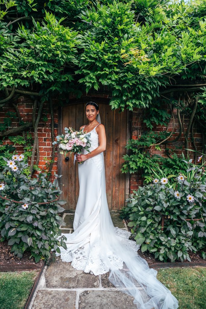 bride stands in walled doorway under greenery