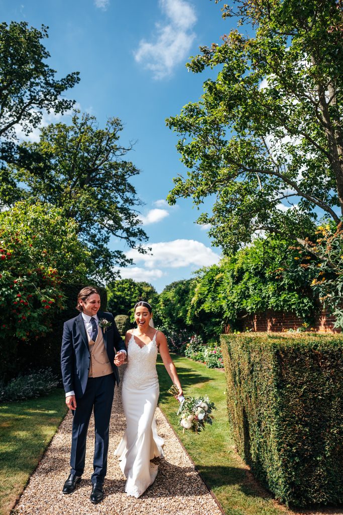 bride and groom walk hand in hand in gardens