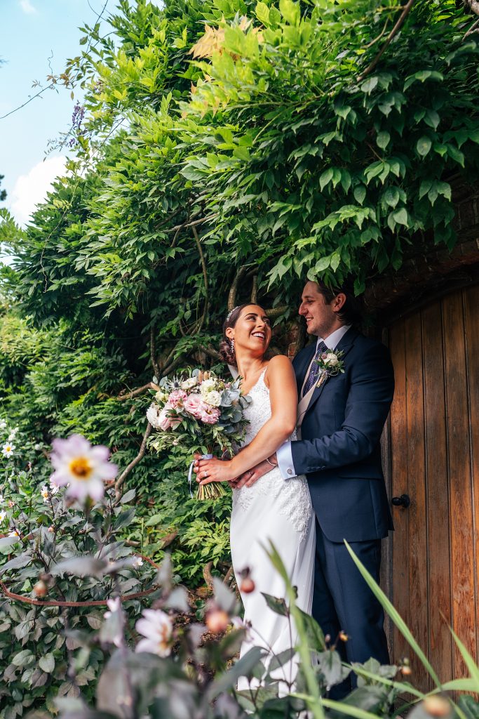 bride and groom stand in lush gardens