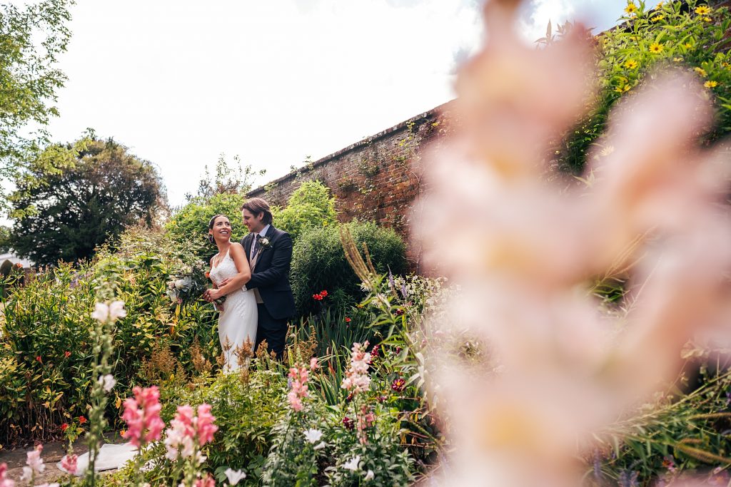 bride and groom stand in lush garden