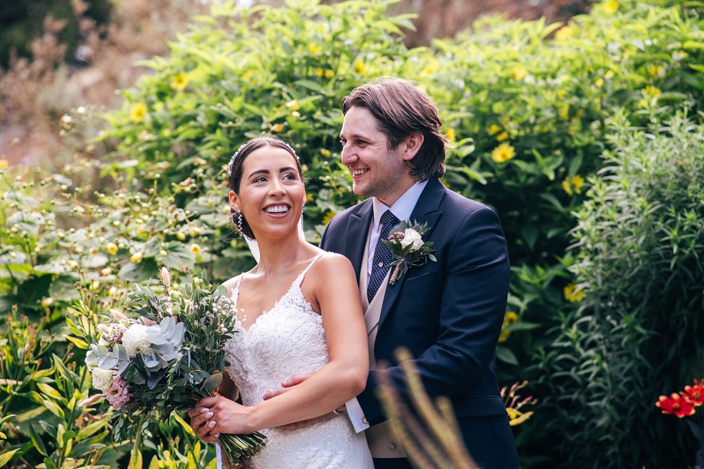 bride and groom stand in lush gardens