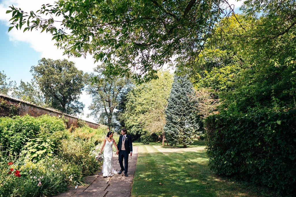wide shot of bride and groom walking in gardens