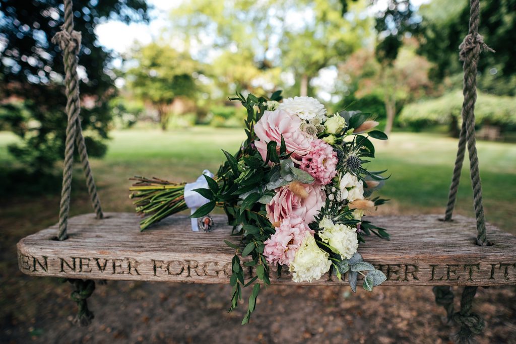 pink and white bouquet sits on swing in gardens