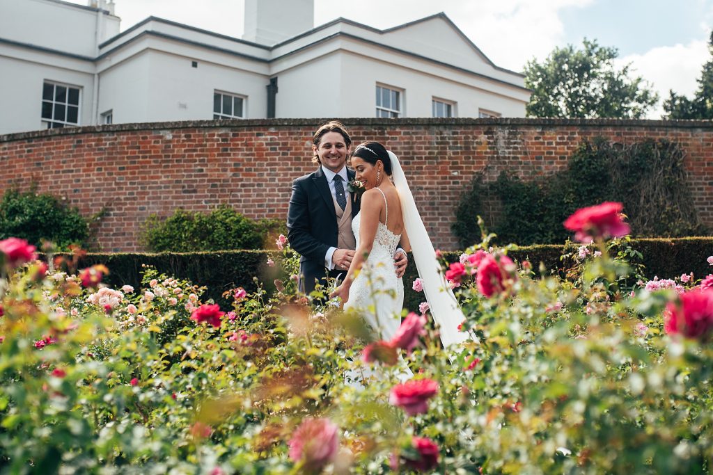 bride and groom in pink rose garden