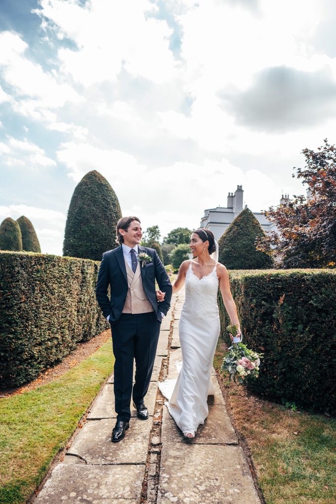 bride and groom walk in manicured gardens