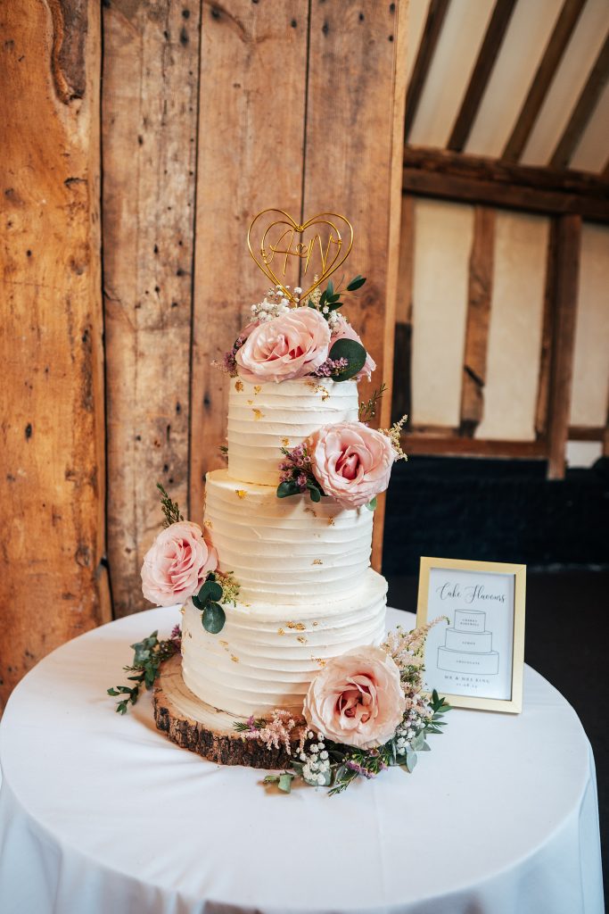 white wedding cake with pink flowers and gold leaf