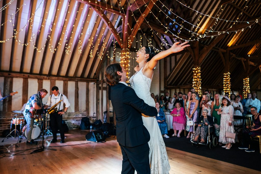 groom lifts bride as she throws arms in air on dance floor
