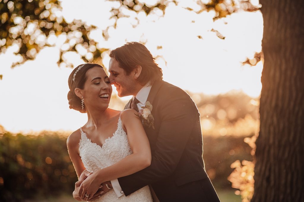 laughing bride and groom in treeline at sunset