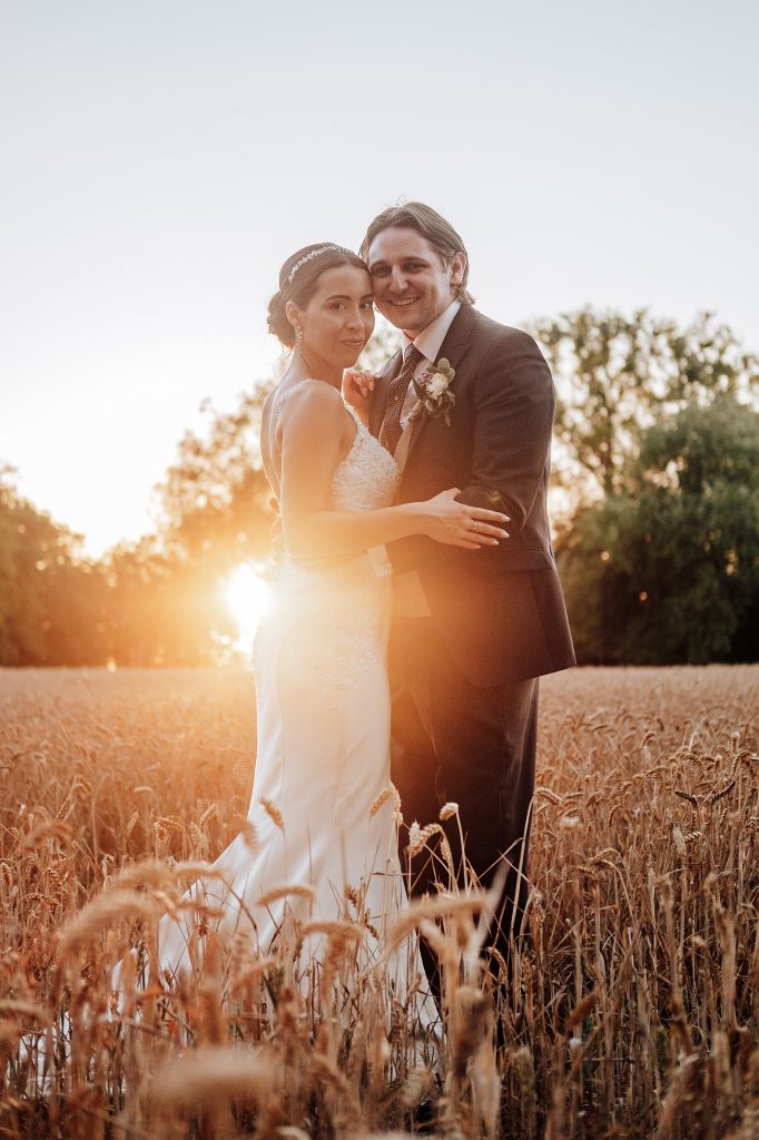 bride and groom in wheat field at sunset