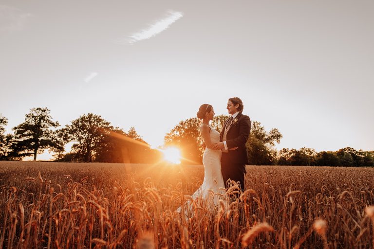 bride and groom in wheat field at sunset