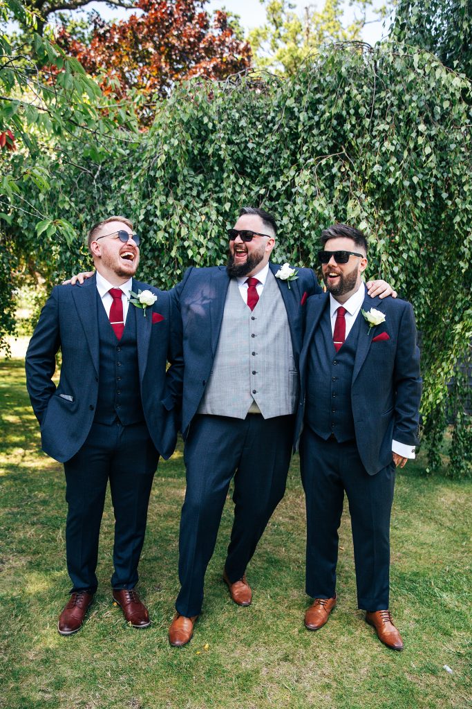 groom laughs with best men in garden