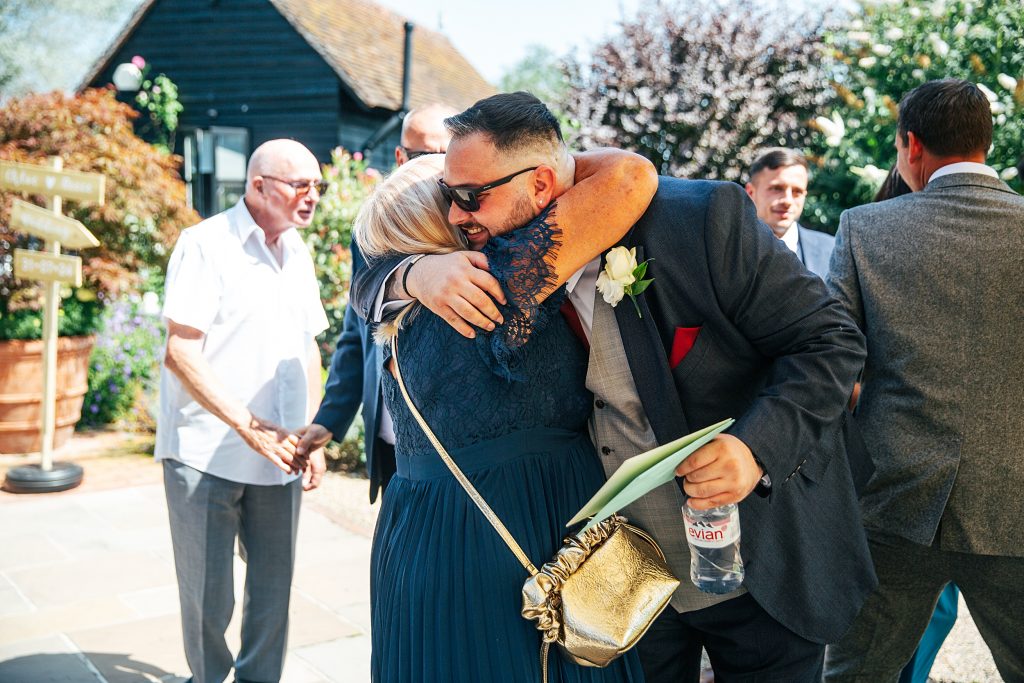 groom hugs wedding guest