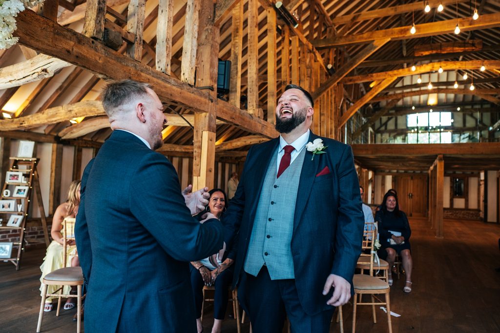 groom laughs with best man as he waits for bride