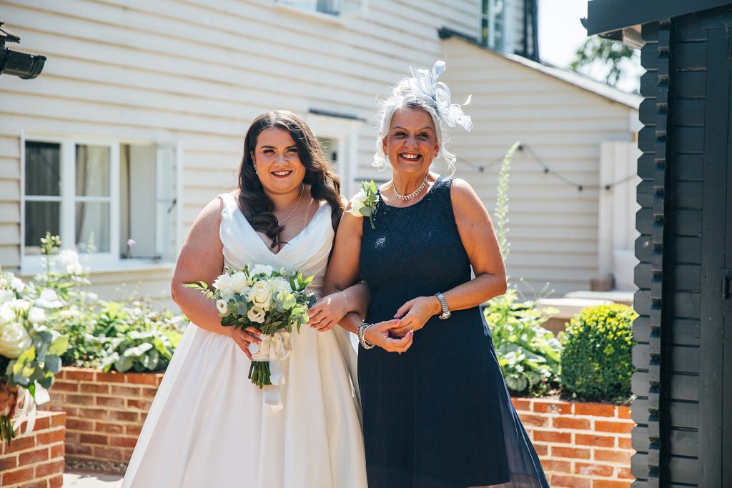 bride smiles with her mum as they wait to go down the aisle