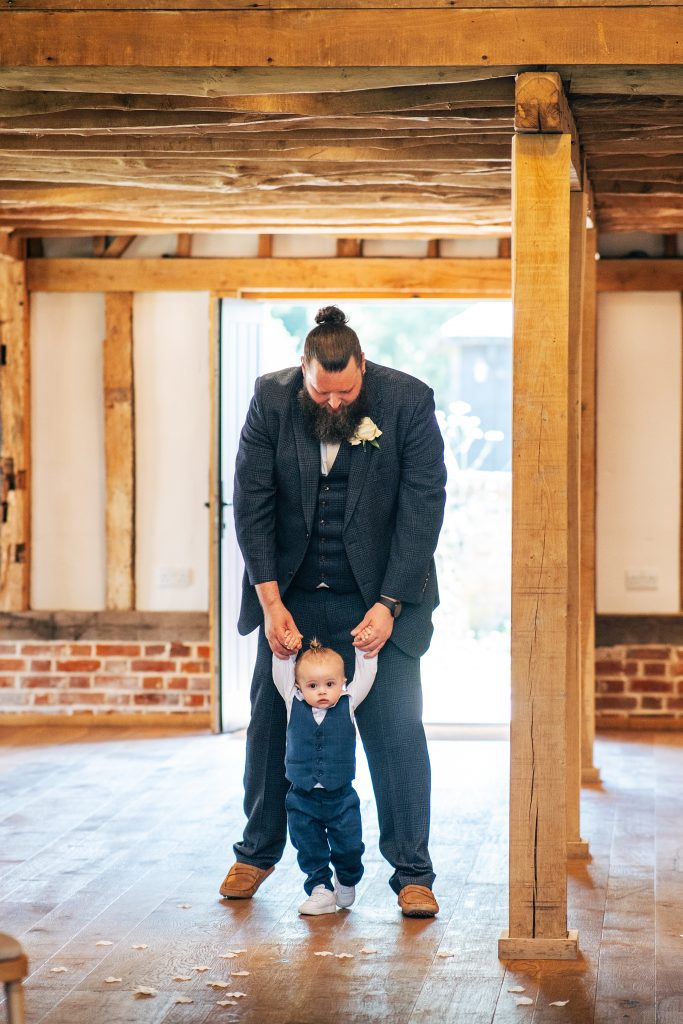 groomsmen walks baby son in suit down aisle