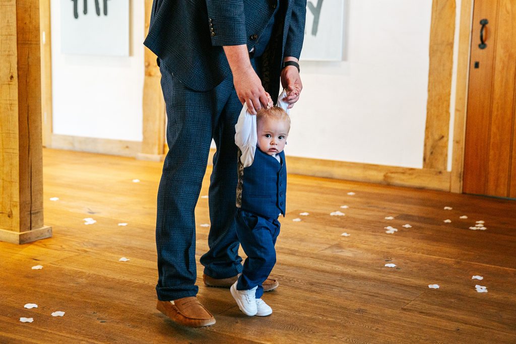 baby boy in suit looks at camera as he walks down aisle