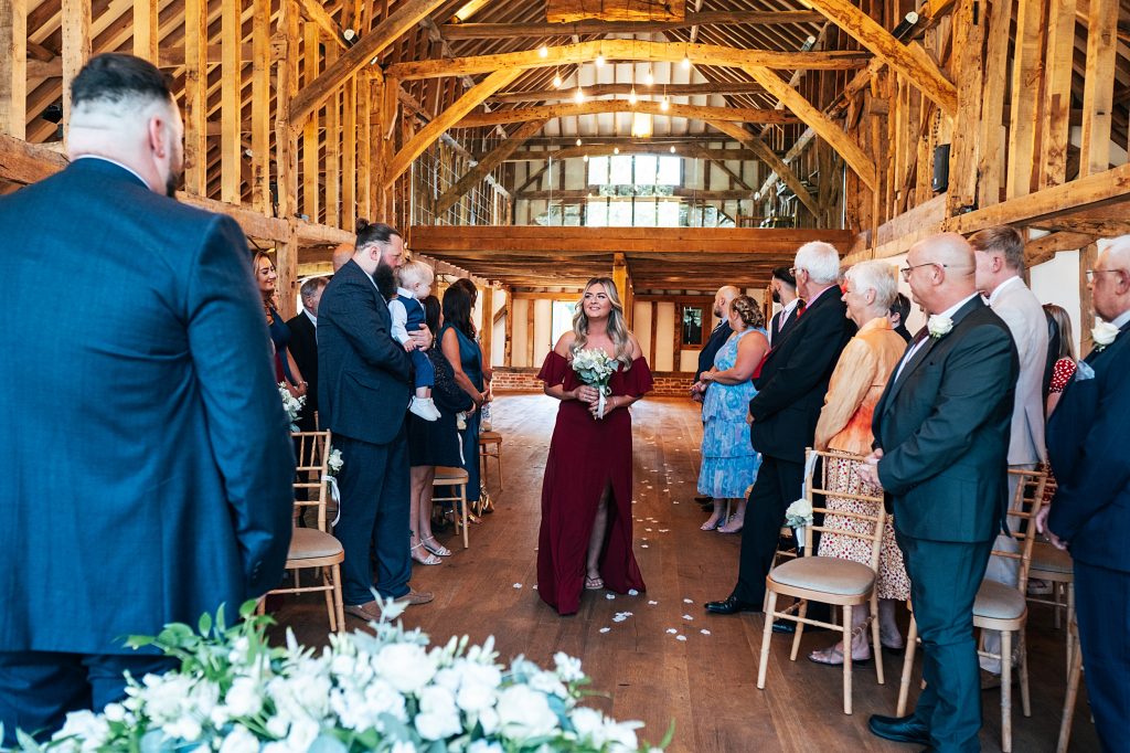 bridesmaid in red walks down aisle