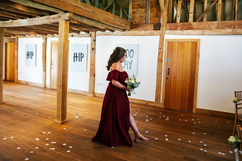 bridesmaid in red walks down aisle