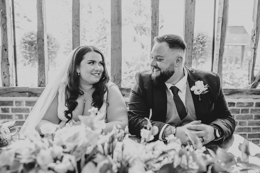 bride and groom look at each other siting at a table
