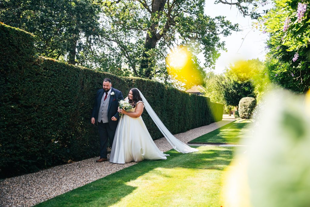 bride and groom walk in gardens at Blake Hall