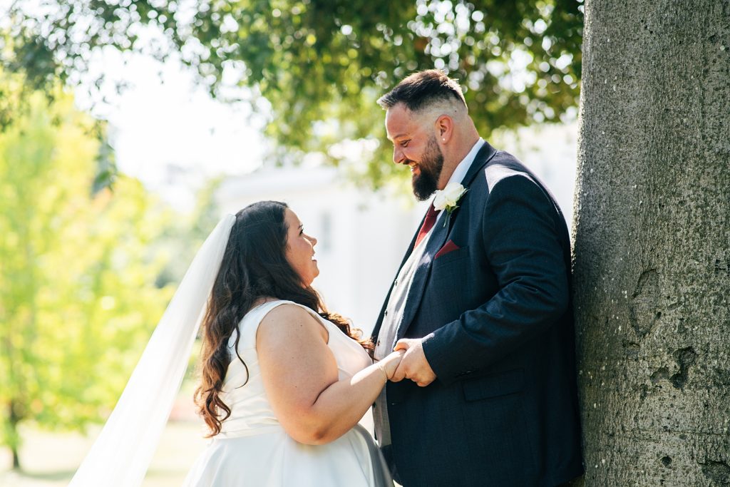 Bride and Groom stand next to tree in garden
