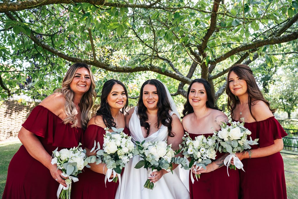 bride with bridesmaids in red under tree