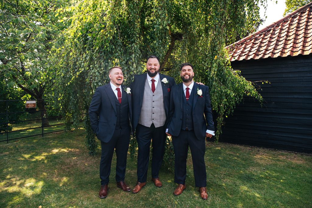 Groom and best man laugh in garden