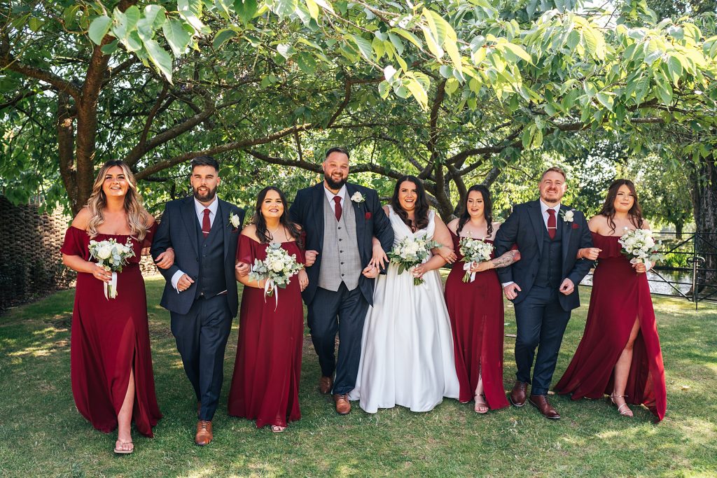 bride groom and wedding party laugh and walk towards camera