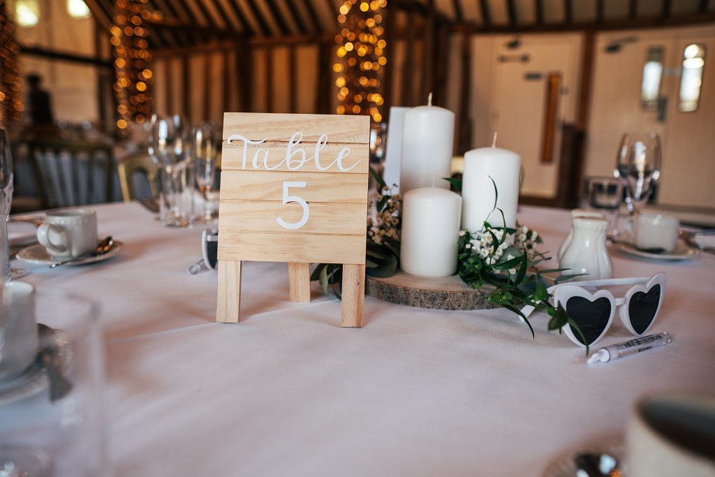 wedding table detail with table number, candles and greenery