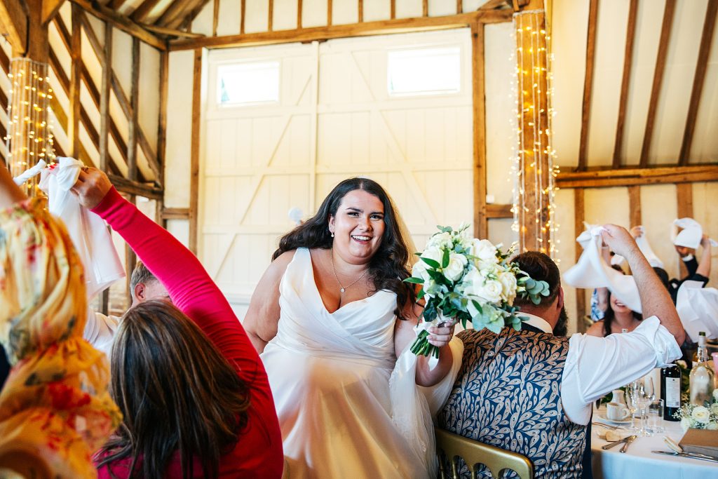 bride enters wedding breakfast as guests wave napkins