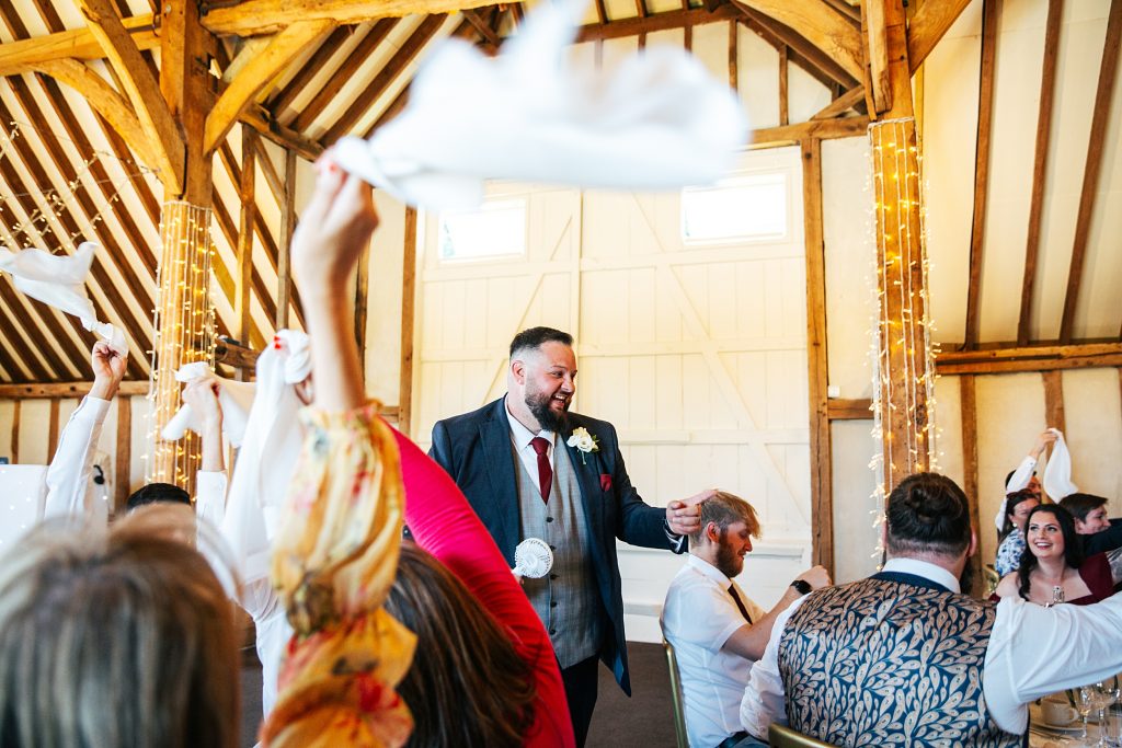 groom enters wedding breakfast as guests wave napkins