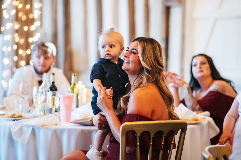 bridesmaid holds up baby boy during speeches
