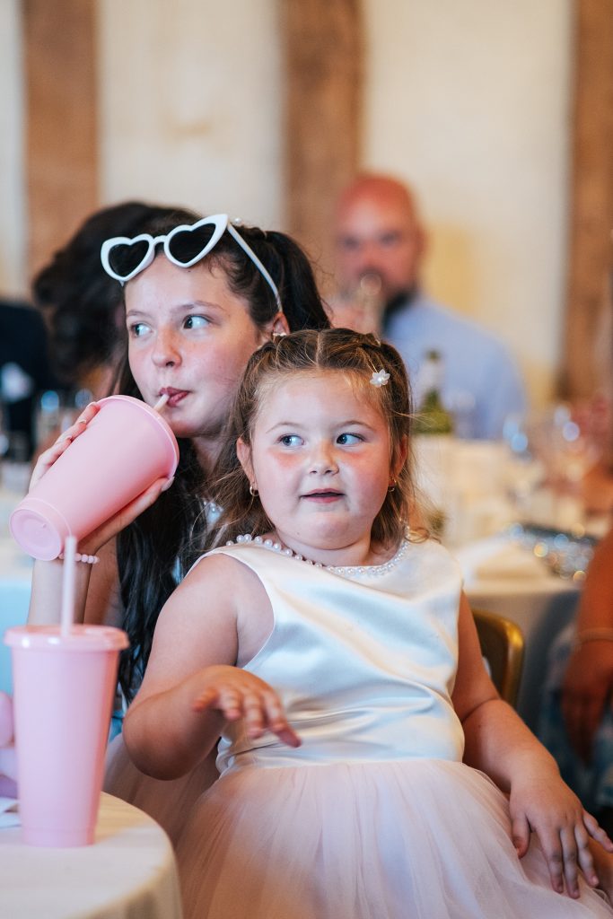 flower girl sits on older girls lap during speeches