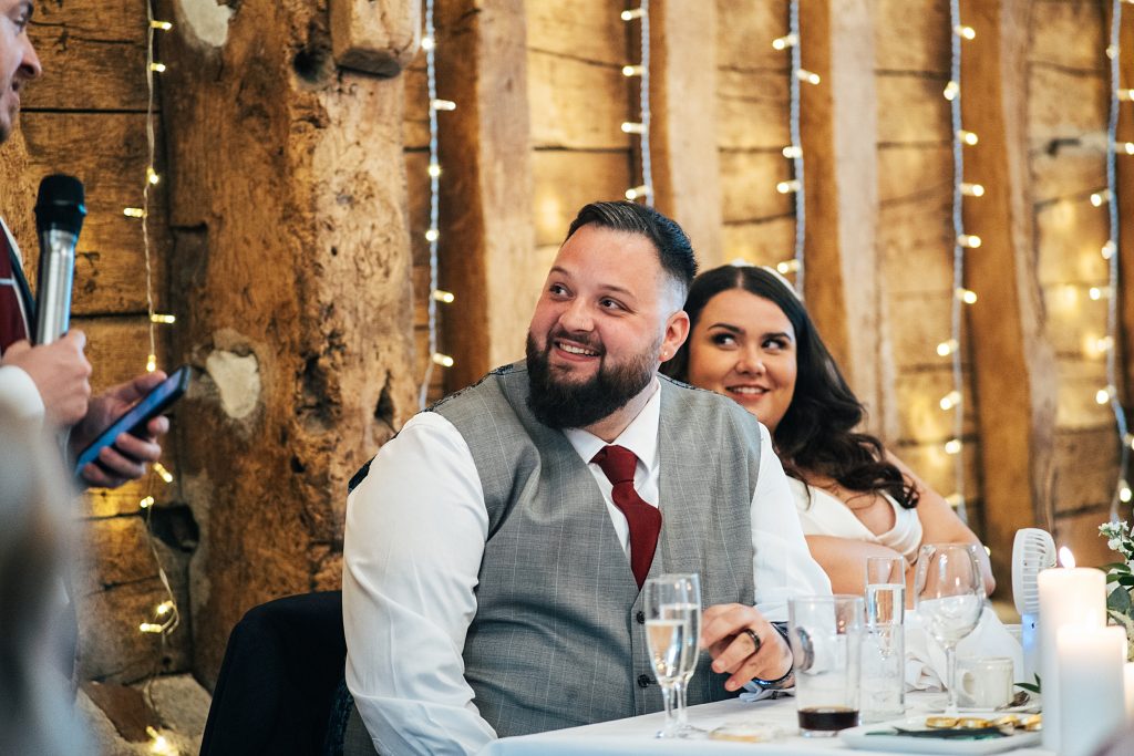 groom smiles during speeches