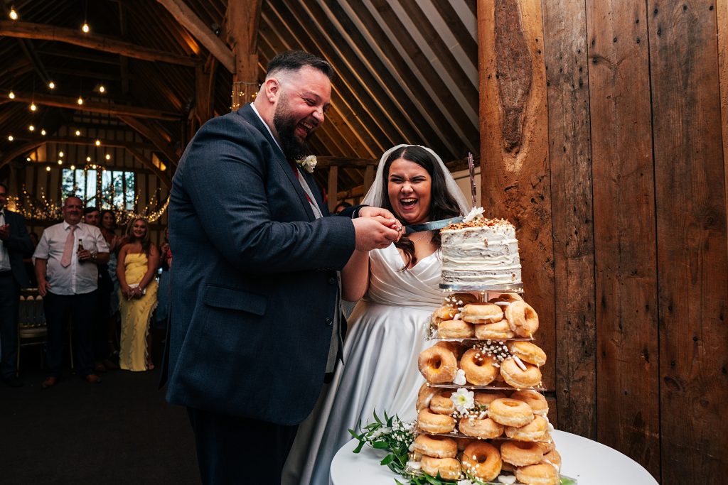 laughing bride and groom cut cake